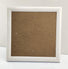 White Craft Buddy Greetings Card frame with brown backing board, photographed on table against white background