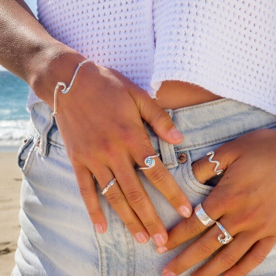 Model wearing Silver Origins Cornish Catch Ring plus variety of other sterling silver rings and wave bracelet